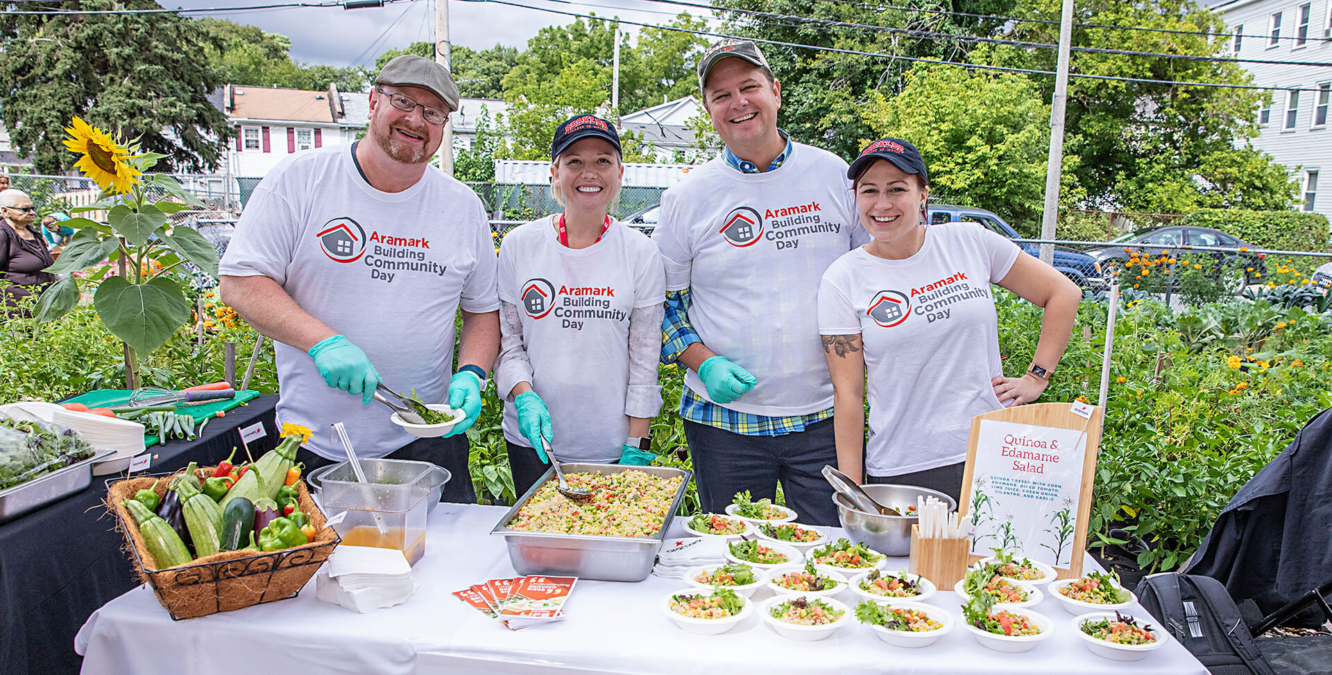 Volunteers at Aramark's Building Community Day serving freshly-made food in a garden.